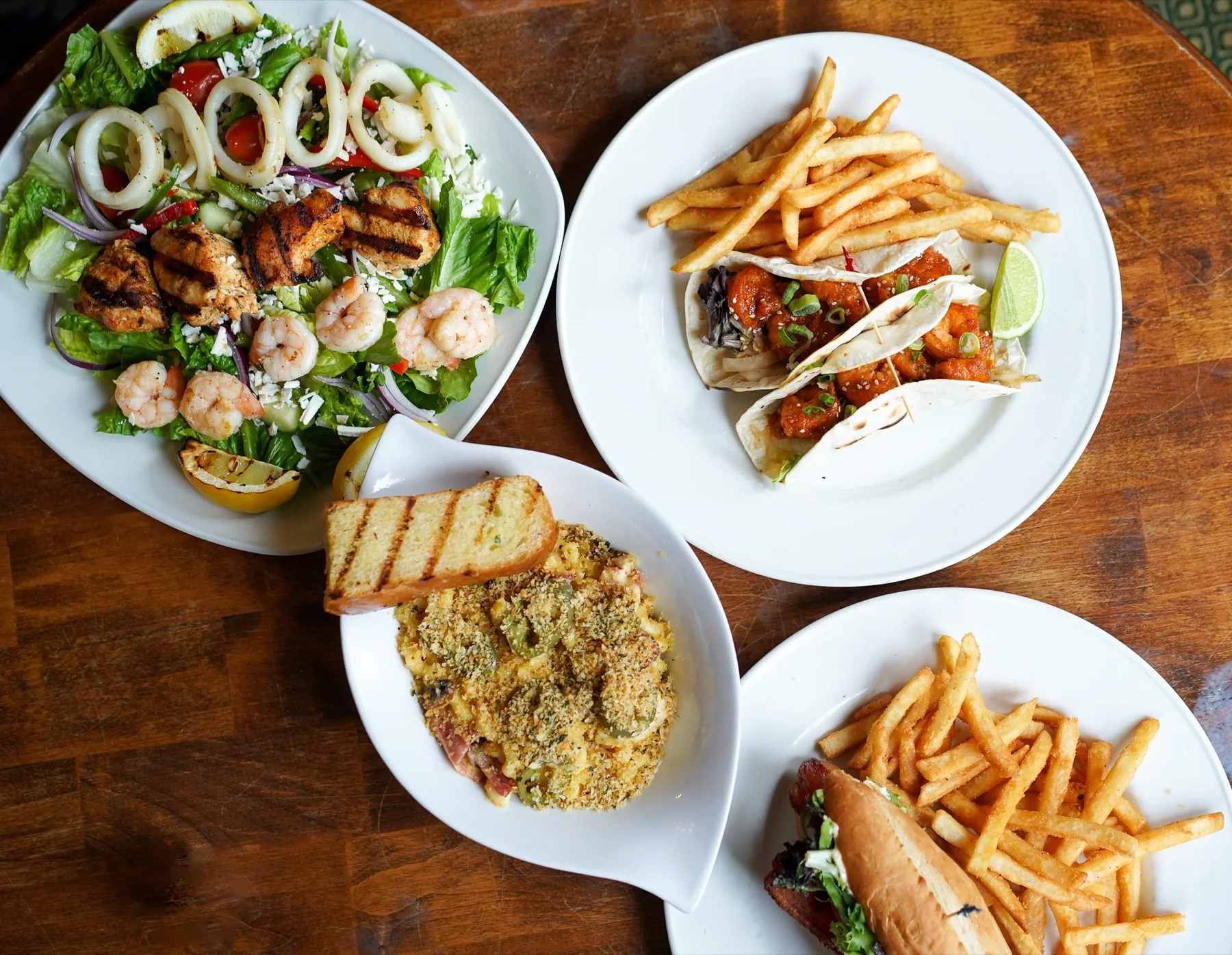 Pub food spread with salad, tacos, mac and cheese, burger, and fries